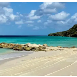 Playa Porto Marie em Curaçao é uma deslumbrante praia na Baía de Porto Marie, conhecida por ser um ponto de partida popular para mergulho e snorkeling. Administrada pela propriedade privada Plantages PortoMari, a praia possui recifes de coral artificiais para melhorar o ecossistema marinho. Seu "recife duplo" único é acessível da costa, proporcionando uma experiência fascinante para atividades aquáticas. A praia também oferece trilhas naturais para caminhadas e mountain bike a partir do estacionamento. Aberta diariamente, a Playa Porto Marie possui um bar e restaurante à beira-mar, com gestão ambiental responsável, incluindo reciclagem de água e materiais sustentáveis. É um refúgio paradisíaco na costa oeste de Curaçao.