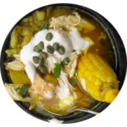 Ajiaco é uma reconfortante canja de galinha colombiana, densa e farta, preparada com vegetais, temperos, frango e ervas, e servida com alcaparras e creme. Esta sopa é uma especialidade popular, com diferentes versões em várias regiões colombianas. O Ajiaco Santafereño, feito com frango, três tipos de batata, milho e a erva guascas, é uma opção reconfortante e deliciosa, especialmente na capital Bogotá. A receita tradicional é cozida em panelas de barro, mas uma panela grande comum também serve. Cada região tem suas variações, mas a essência permanece, oferecendo uma refeição perfeita para os dias frios.