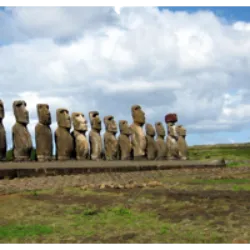 A Ilha de Páscoa, também conhecida como Rapa Nui, está situada no sul do Oceano Pacífico, a 3.700 km da costa oeste do Chile. Famosa por suas estátuas de pedra, os moais, é parte da Região de Valparaíso e tem como idiomas oficiais o Espanhol e o Rapanui. Colonizada por polinésios, sua ocupação remonta a cerca de 900 d.C. A ilha foi descoberta pelo explorador neerlandês Jacob Roggeveen em 1722. Durante a colonização europeia em 1888, foi anexada pelo Chile, tornando-se uma fazenda de ovelhas. Os nativos foram escravizados, mas só em 1966 foram reconhecidos como cidadãos chilenos. A Ilha de Páscoa, de forma triangular e vulcânica, apresenta uma topografia desafiadora e um clima que limita as fontes de alimento e água potável. Atualmente, o turismo impulsiona a economia da ilha.