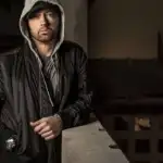 
Usando as iniciais de seu nome, Marshall Bruce Mathers III, Eminem criou seu nome artístico: EM-IN-EM. No entanto, devido à existência de uma marca de chocolates icônica com o mesmo nome, o artista teve que modificar a grafia para se manter afastado da confusão. Após o segundo divórcio, seu vício em drogas e álcool aumentou e culminou em uma overdose de remédios para dormir e analgésicos, o que causou um choque ao mundo da música. Como resultado dessa luta pessoal, Eminem mudou a orientação das suas letras musicais para um tom mais motivador e direcionou os seus álbuns 