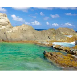 Em meio a uma formação rochosa peculiar, pedras vulcânicas cercam uma pequena depressão, originando a serena Piscina Natural de Aruba, também conhecida como 